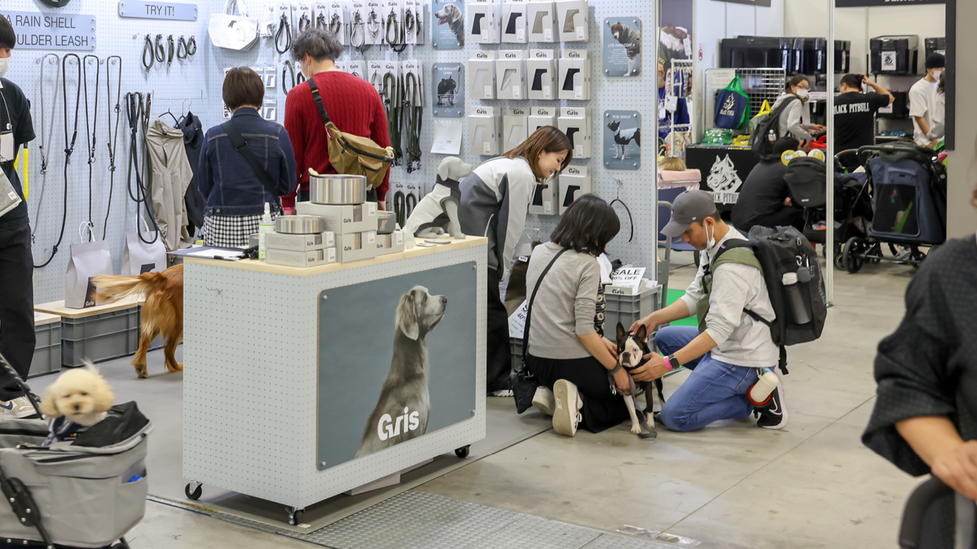 Besucher mit Hunden an einem Messestand mit Produkten für den Hund
